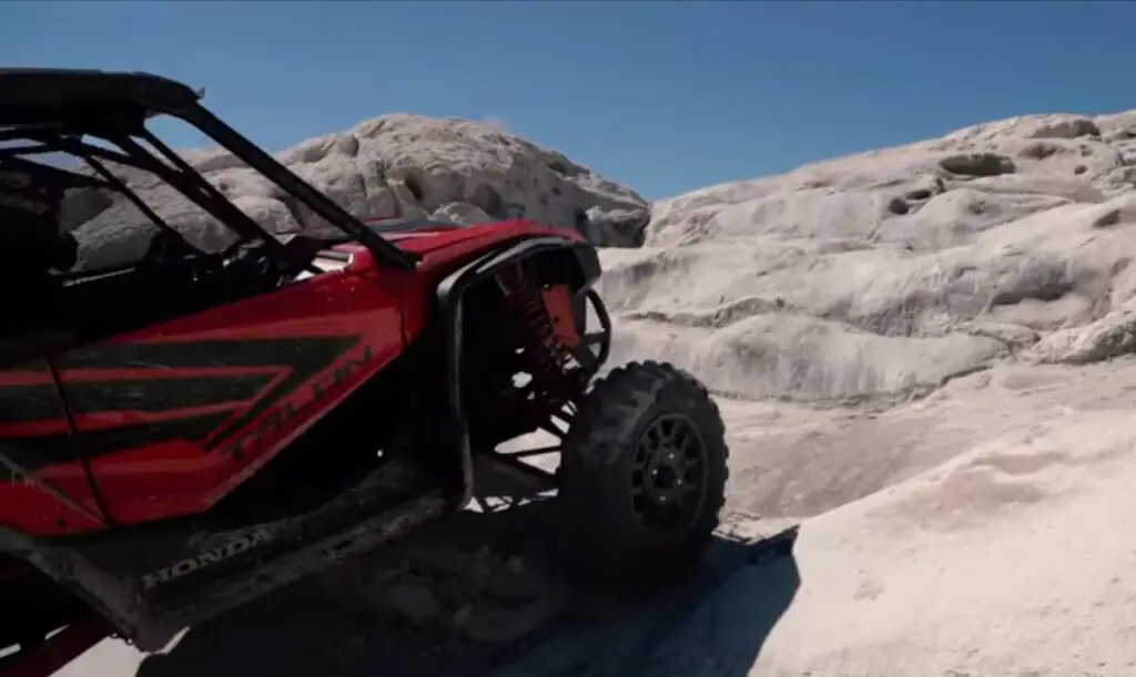 A Honda Talon is climbing a rocky hill.