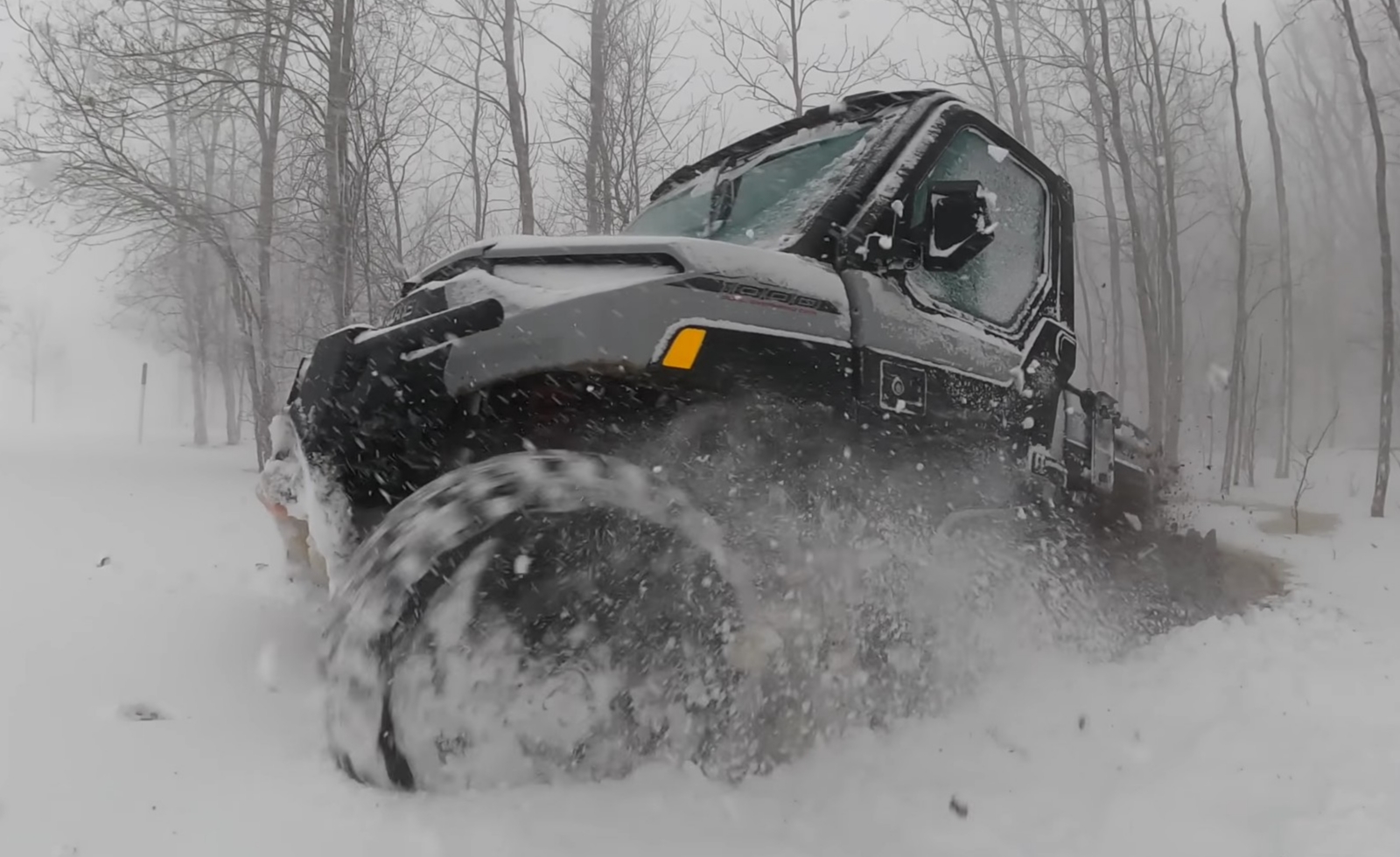 A Polaris Ranger NorthStar is being driven through a deep snow road.