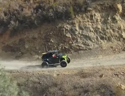 A Polaris UTV is being driven through a hill road.