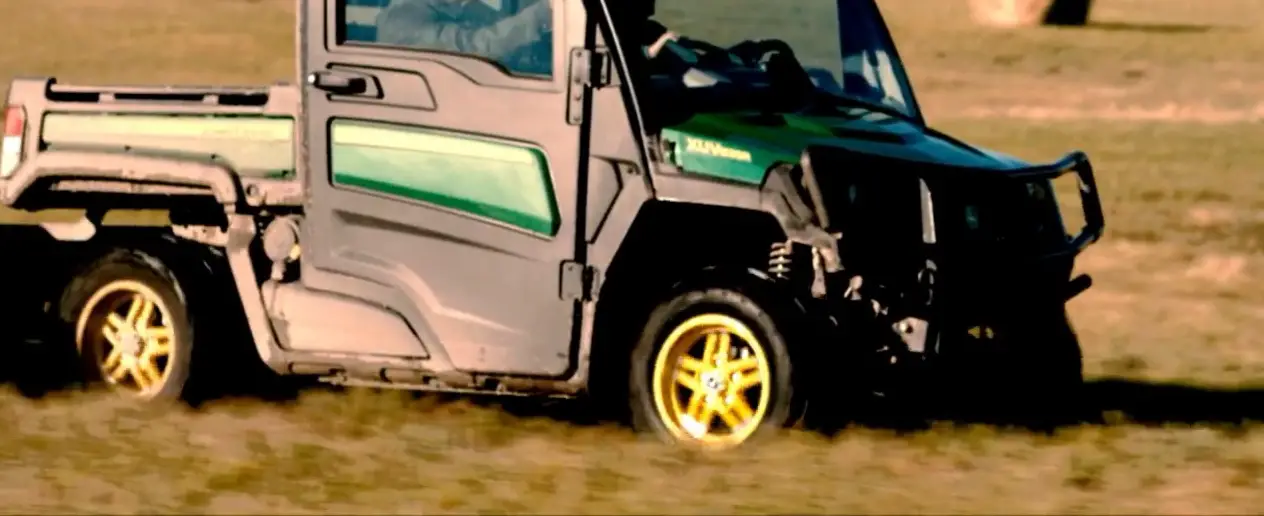 A John Deere Gator XUV835M is being driven through a green field.