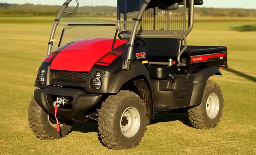 A Kawasaki Mule is parked in a green field.