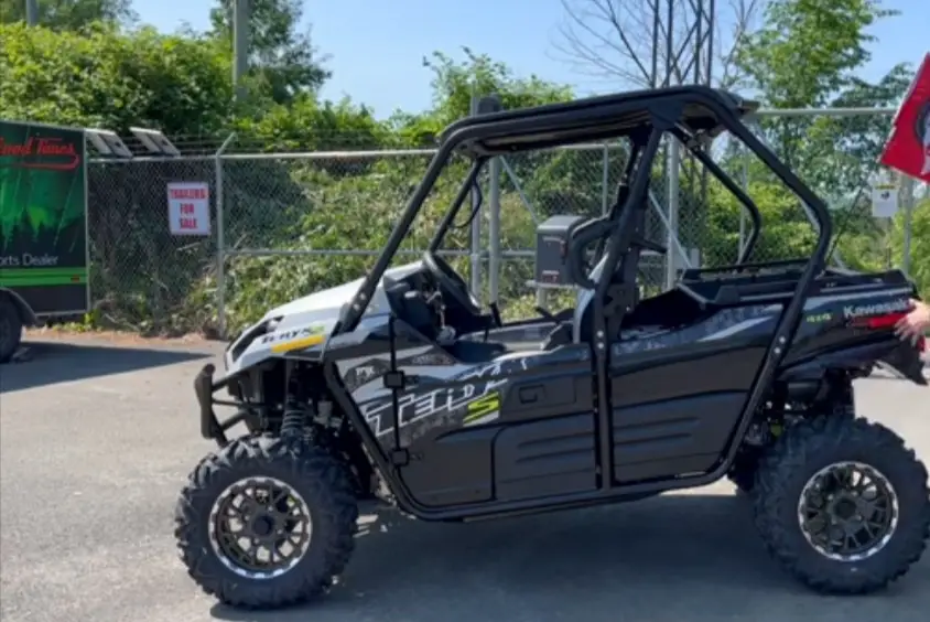 A Kawasaki teryx is parked in a parking lot.