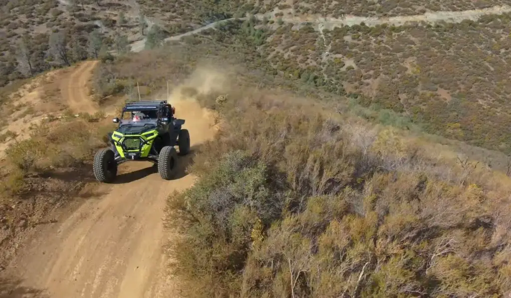 A Polaris UTV is being driven through a dirt road.