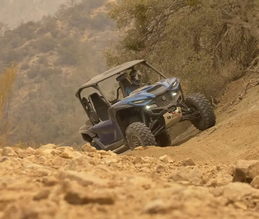 A Yamaha Wolverine RMAX2 is being driven through a hill road.