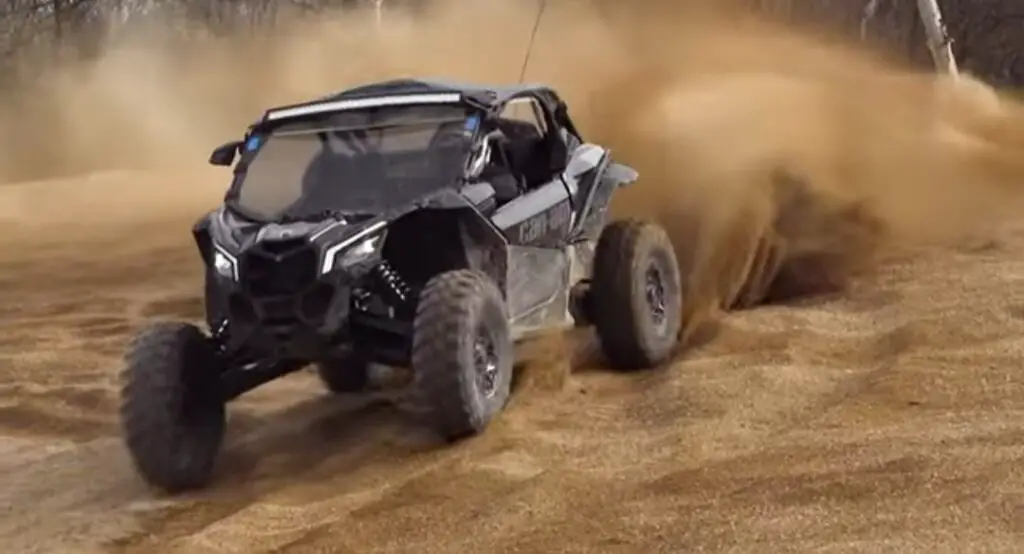 A Maverick X3 DS is being driven through a sandy surface.