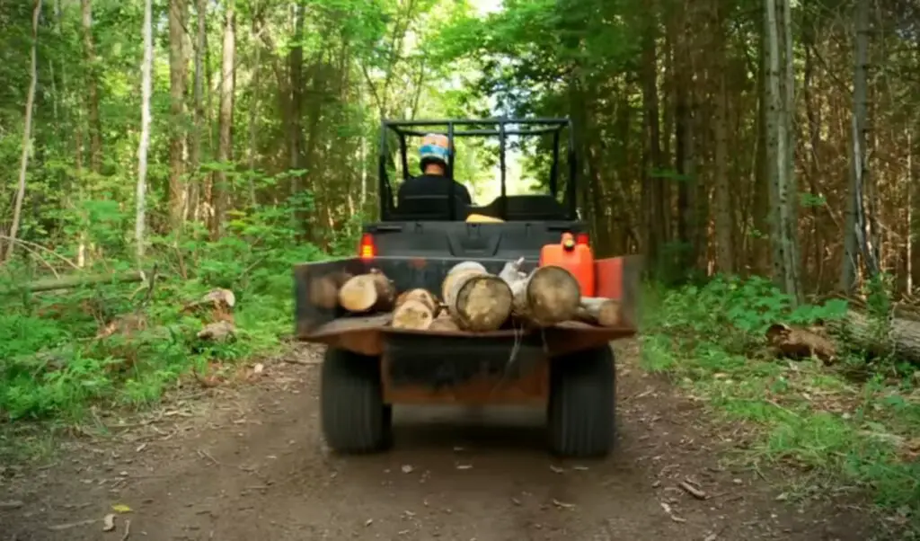 A Polaris Ranger 500 is carrying some woods through a jungle terrain.