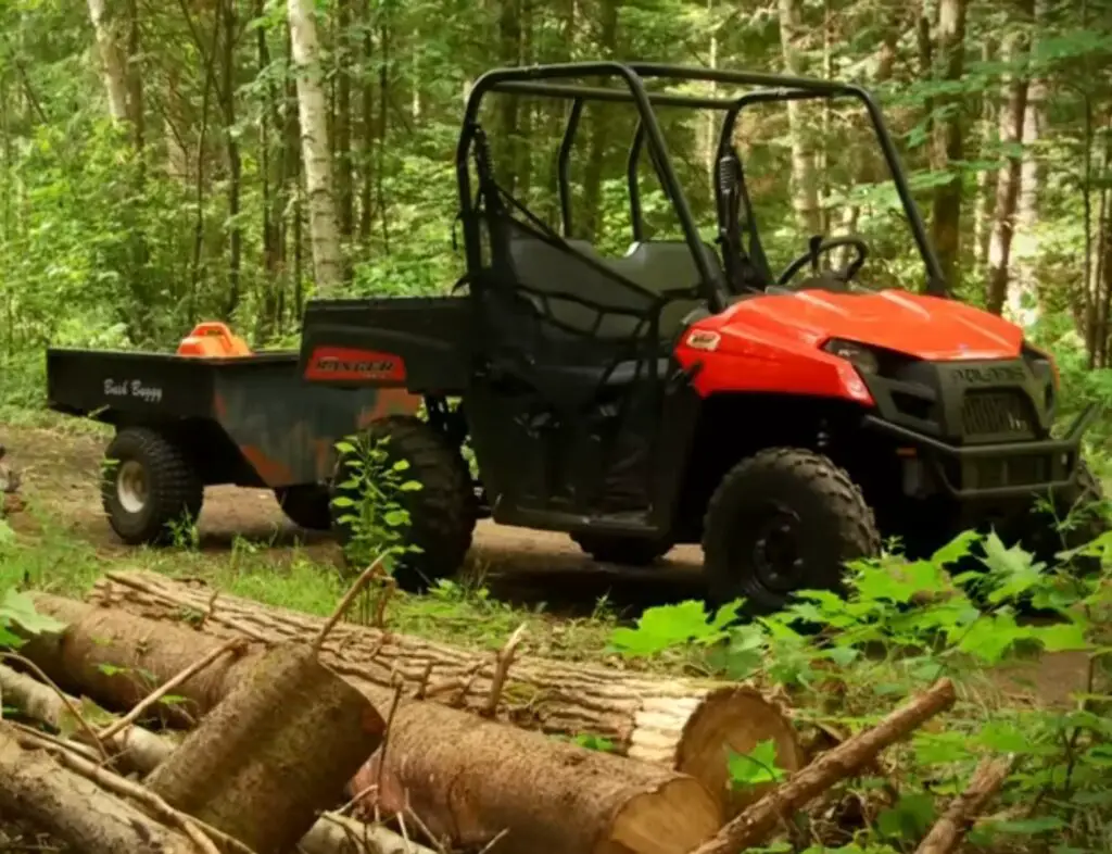 A Polaris Ranger 500 is carrying some woods through a jungle terrain.