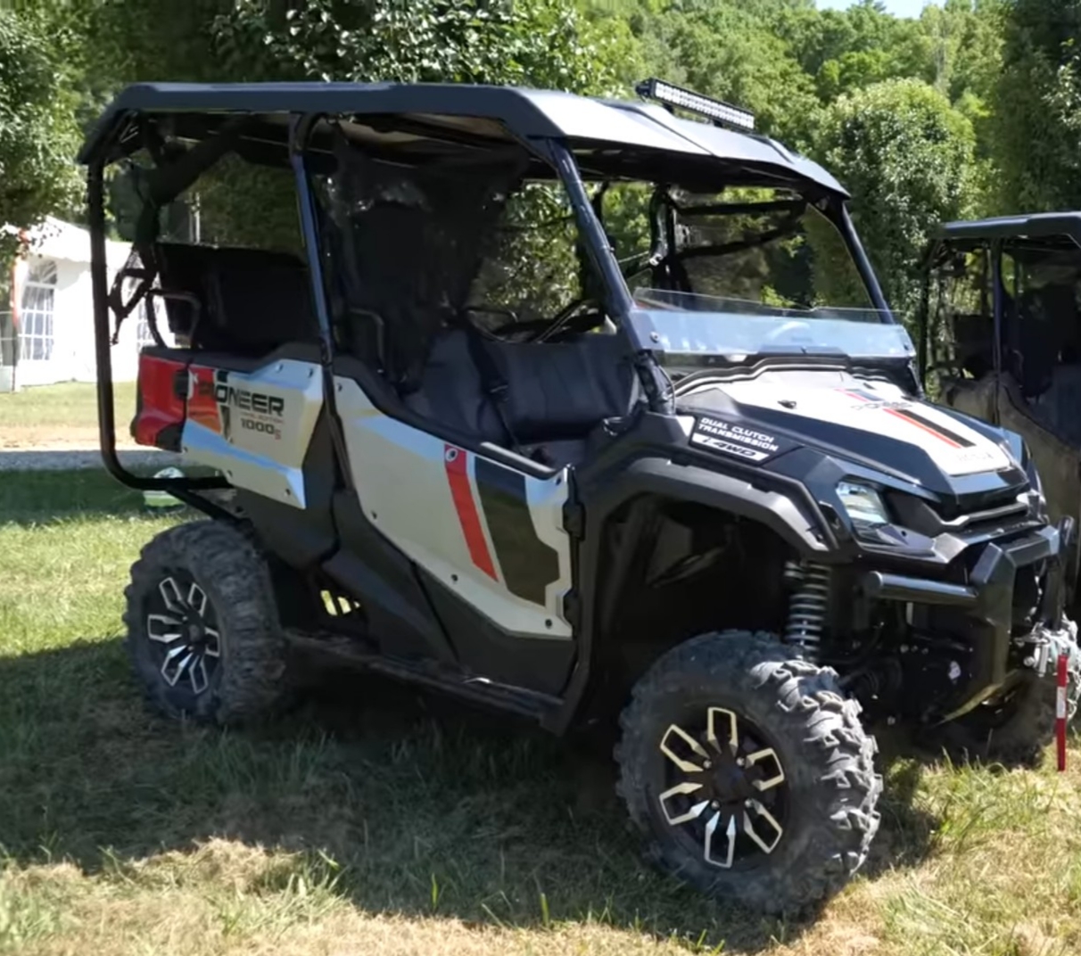 A Honda Pioneer 1000 is parked on a grassy field.