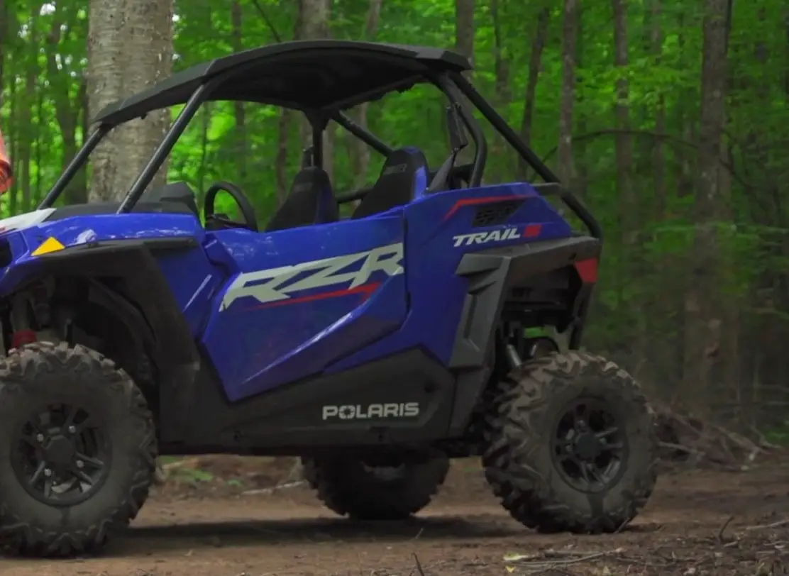 A Polaris RZR 1000 is parked on a dirt jungle terrain.