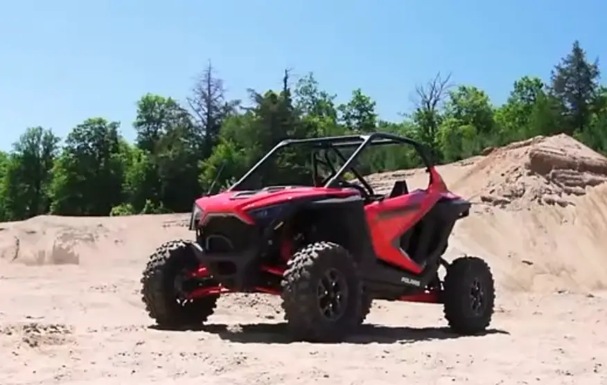 A Polaris RZR PRO XP is parked on a sandy surface.