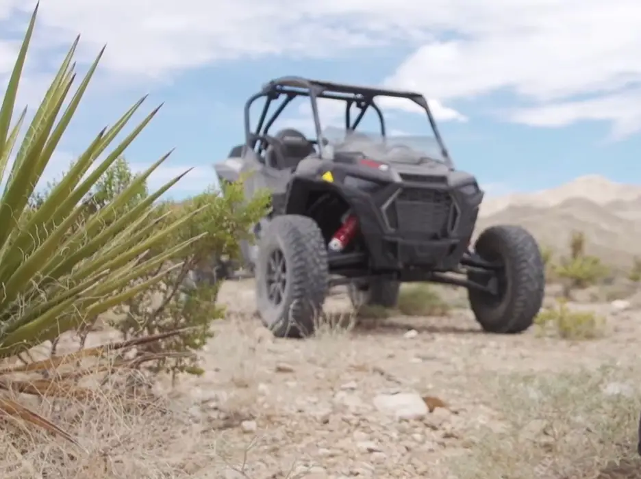 A Polaris RZR Turbo S is parked on a desert field.