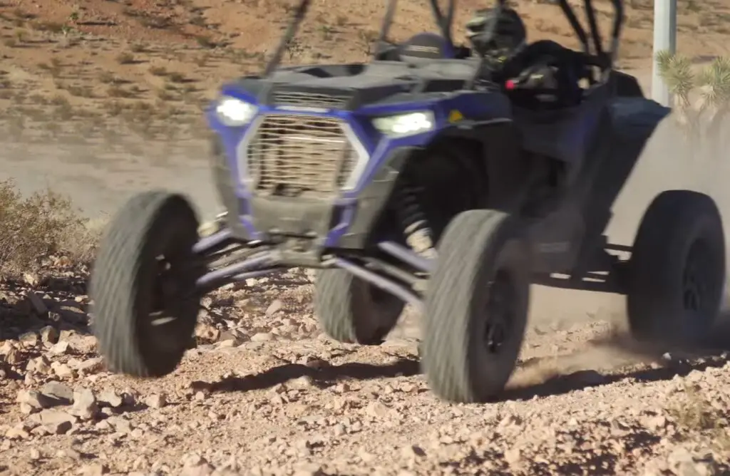 A Polaris RZR XP Turbo S is being driven through a gravel road.