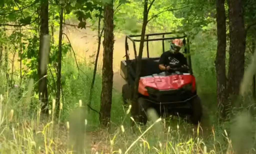 A Polaris Ranger 500 is being driven through a jungle terrain.