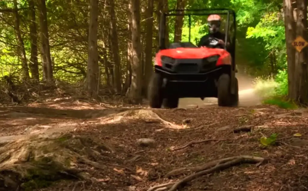 A Polaris Ranger 500 is being driven through a dirt road.