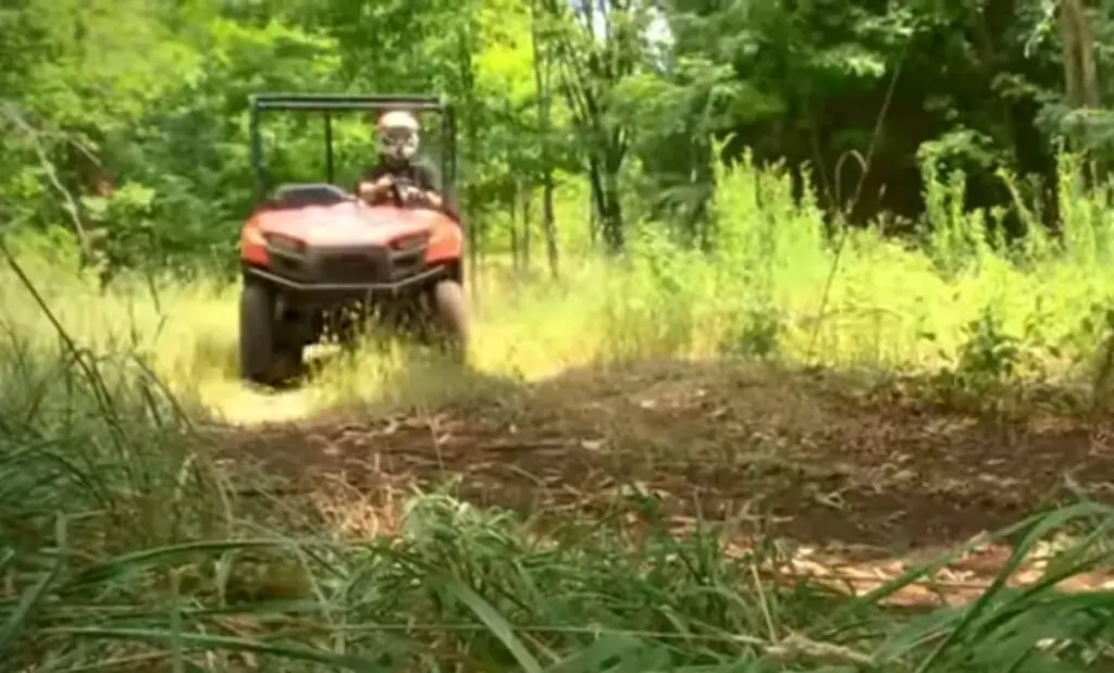 A Polaris Ranger 500 is being driven through a dirt grassy field.