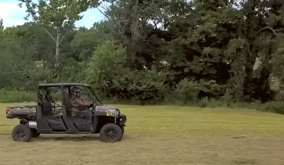 A Polaris Ranger Crew XP 1000 is being driven through a green field.