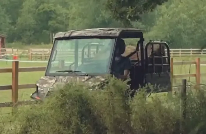 A Polaris Ranger EV with loaded dump bed is being driven through a green field.