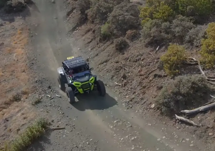 A Polaris UTV is being driven through a dirt road.