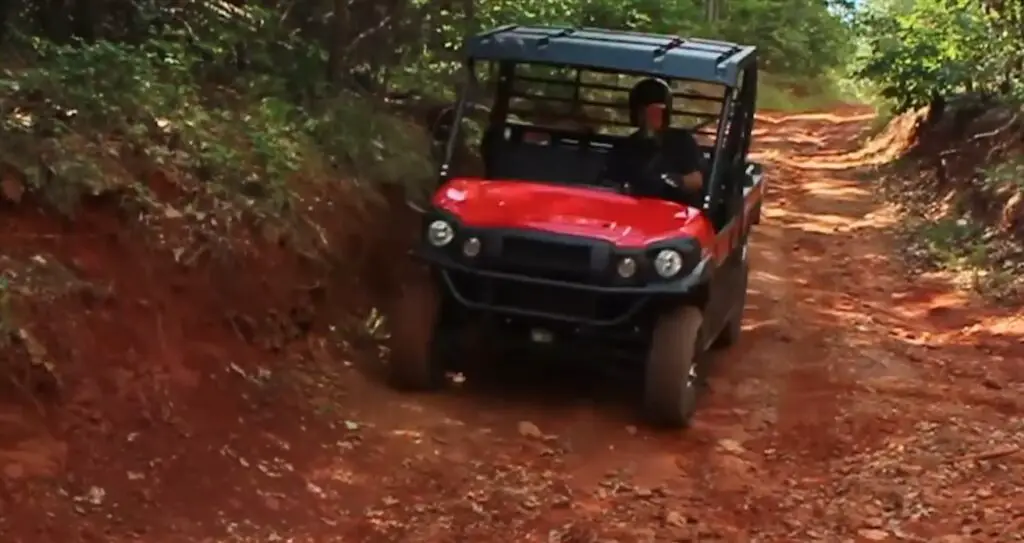 A Kawasaki mule pro FX LE is being driven through a dirt road.