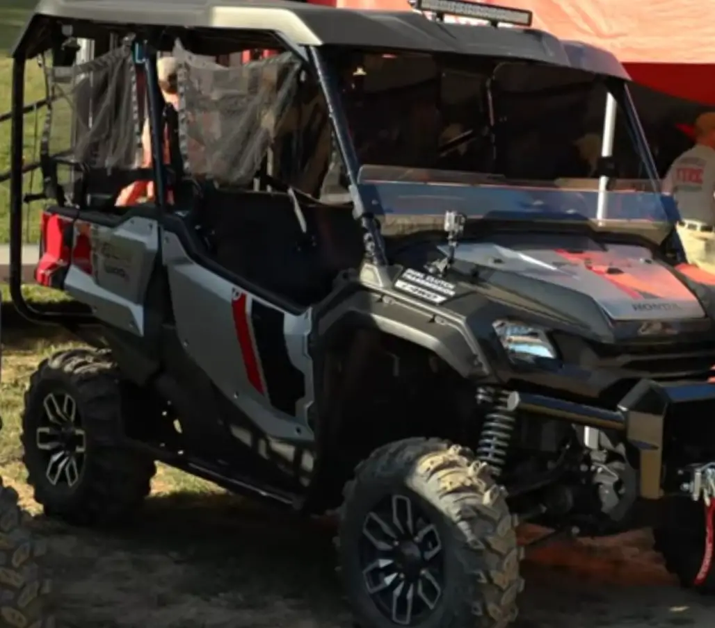 A Honda Pioneer 1000 is parked in front of a tent.