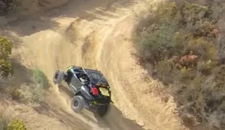 A Polaris Turbo is being driven through a dusty road.