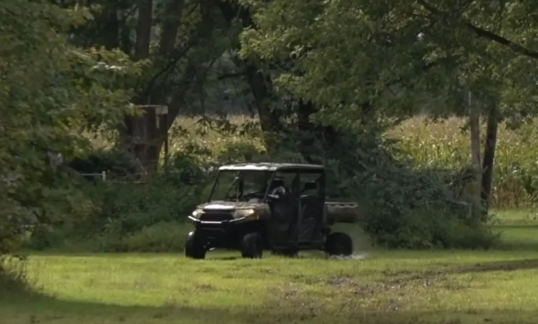 A Polaris Ranger UTV is being driven through a green field.