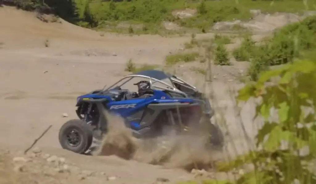 A Polaris RZR is being driven through a desert road.