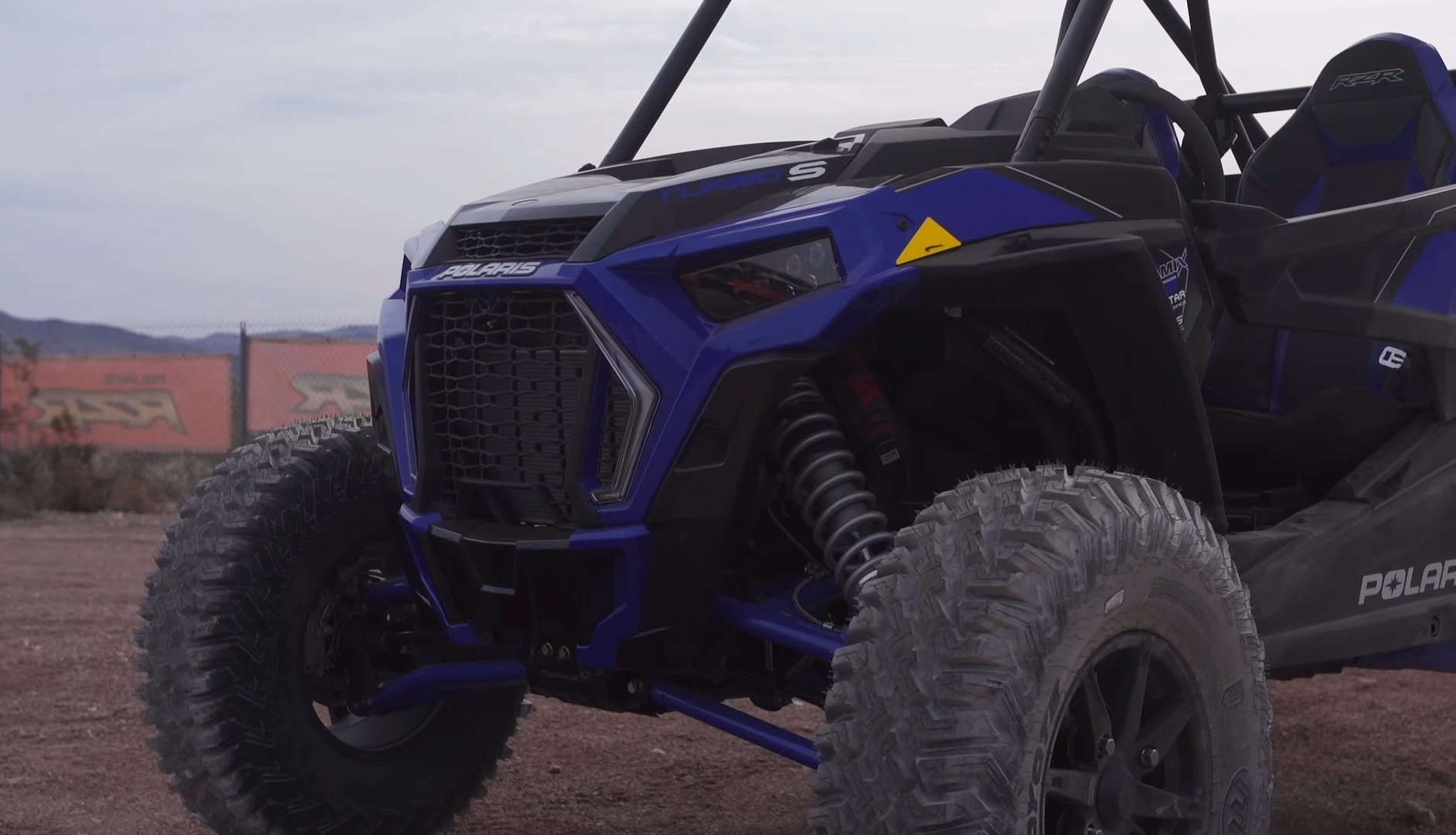 A Polaris RZR XP Turbo S is parked on a dirt surface.