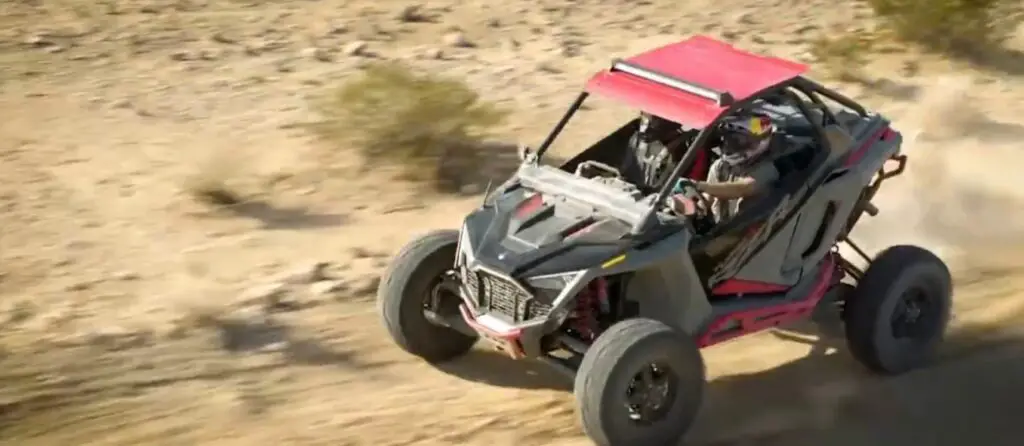 A Polaris UTV is being driven through a dirt road.