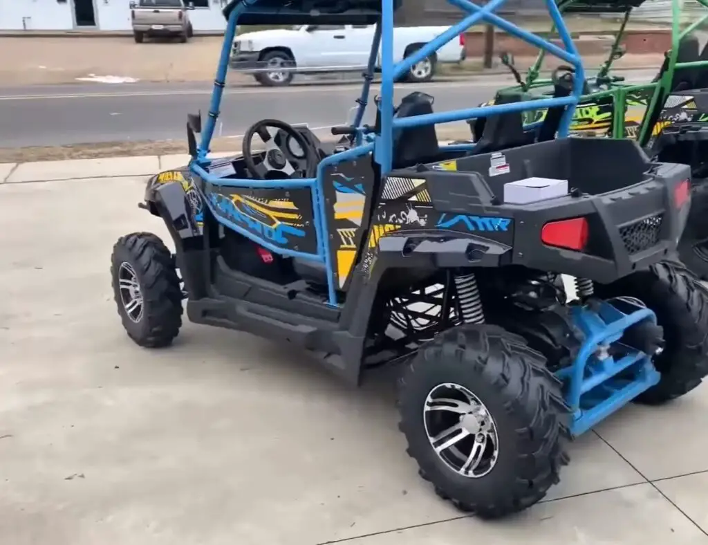 Two child UTVs are parked in a parking lot in front of a road.