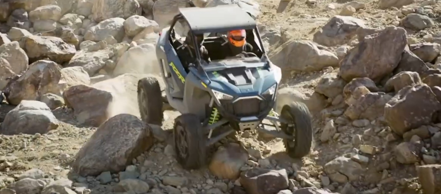 A Polaris RZR is being driven through a rocky terrain.