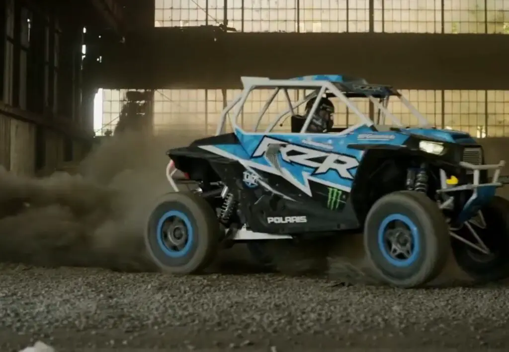 A blue Polaris RZR is taking draft in a warehouse.