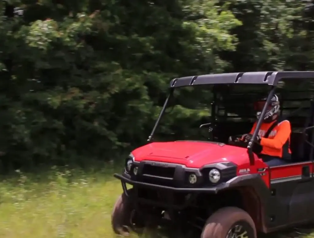 A Kawasaki Mule Pro FX LE is being driven through a grass field.