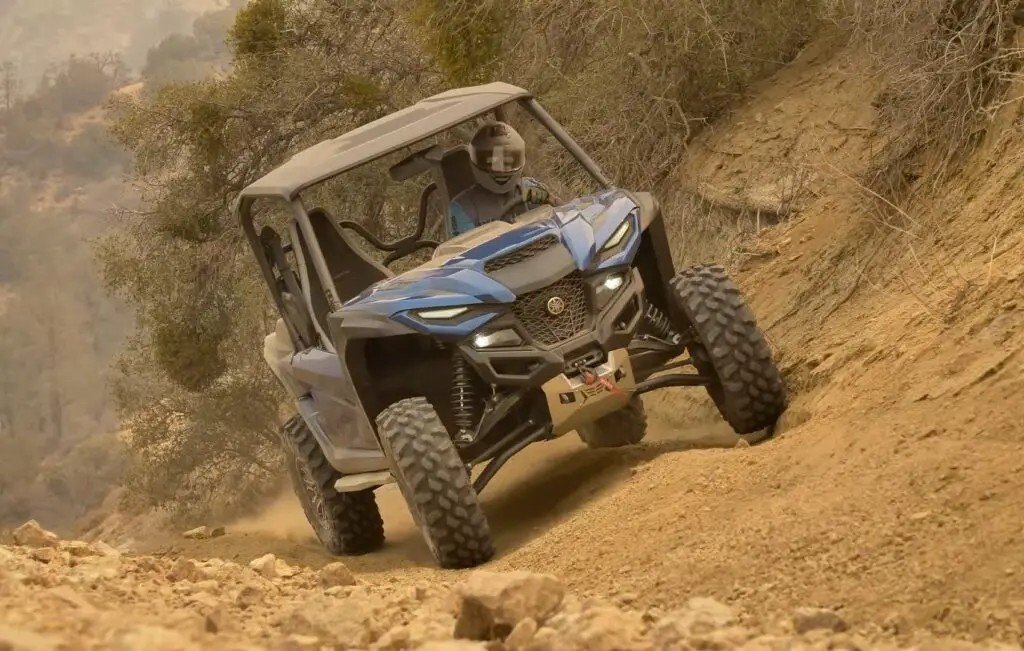 A Yamaha Wolverine RMAX2 is being driven through a rocky mountain road.