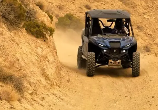 A Yamaha RMAX2 is being driven through a dirt road.