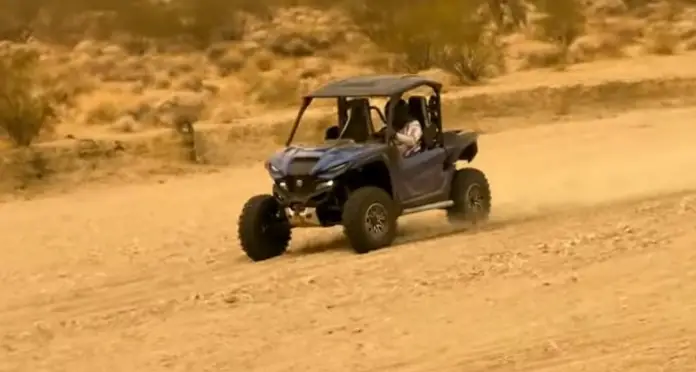 A Yamaha RMAX2 is being driven through a dirt desert road.