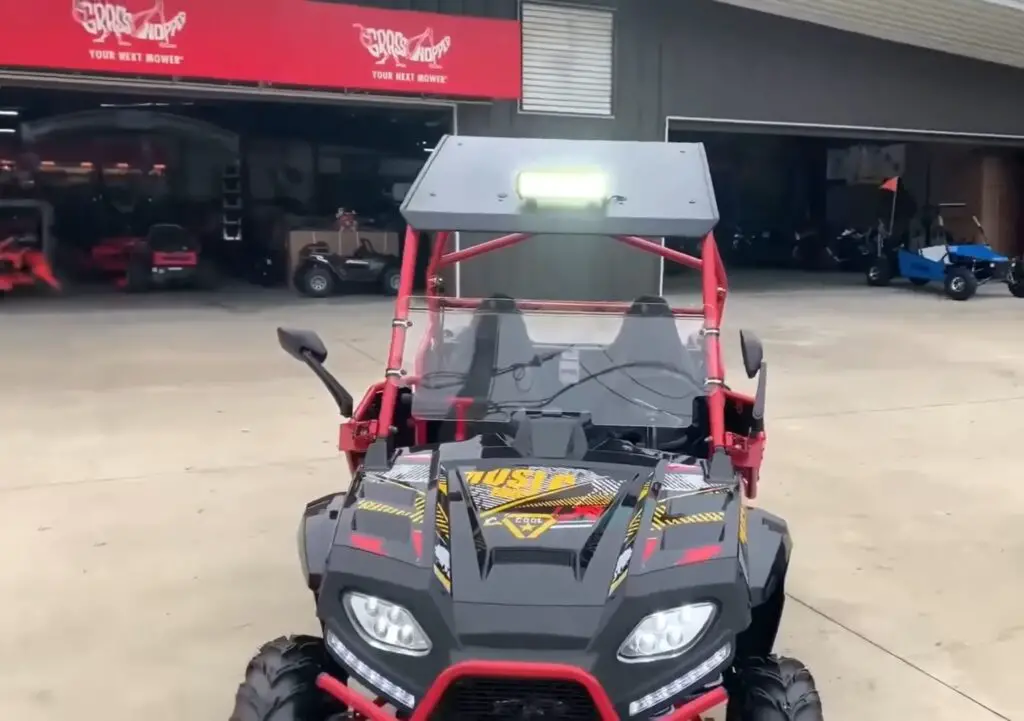 A red and black child UTV is parked in front of a UTV showroom.